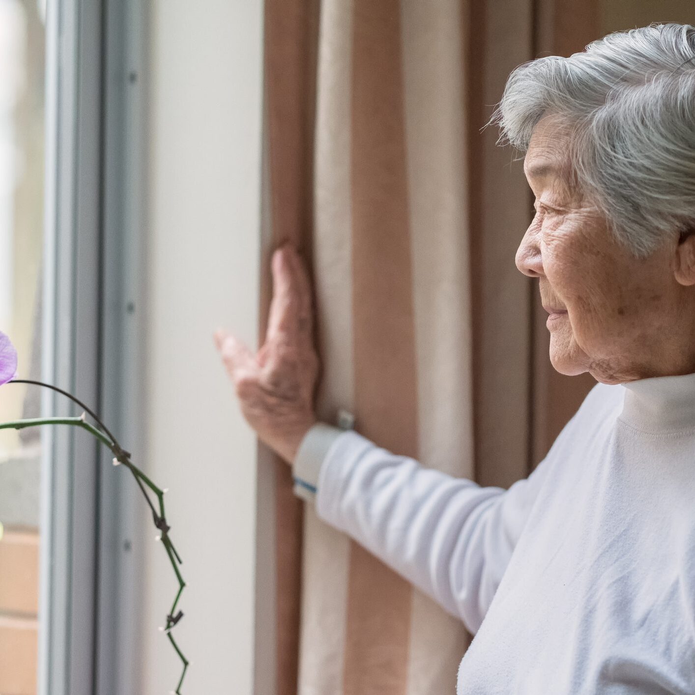 Thoughtful woman looking outside near flower