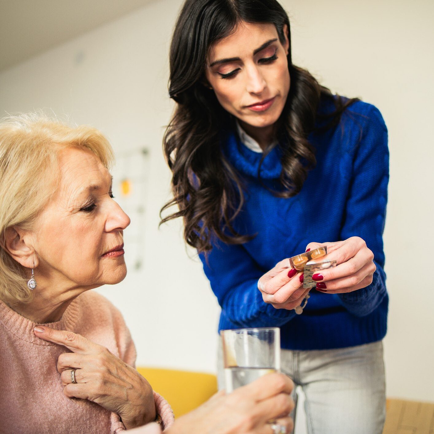Young woman explaining pills to senior