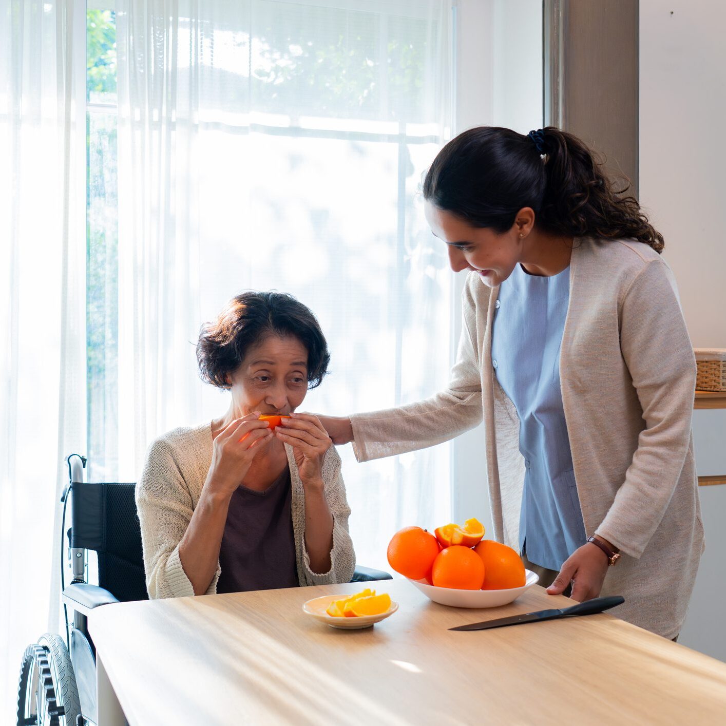 Woman feeding oranges to elderly person
